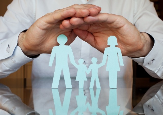 Hands covering paper cut out family