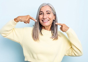 Happy, mature woman pointing at her smile