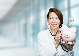 A smiling doctor listening to a piggy bank with a stethoscope
