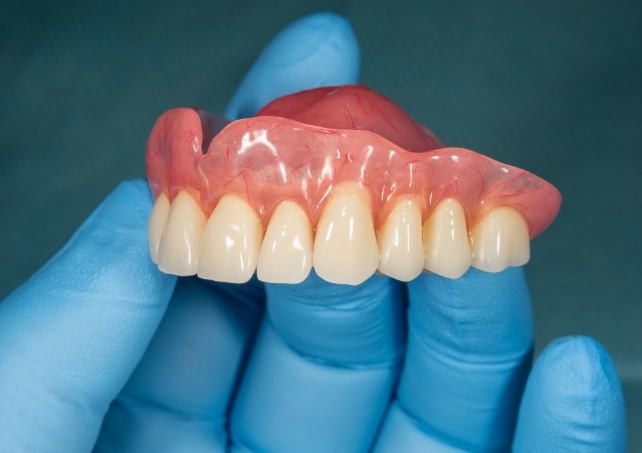 Hand holding a full denture