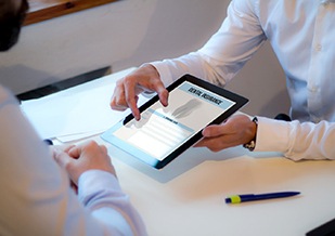 Man and dentist looking at dental insurance form on tablet