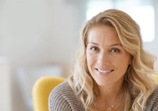 Blonde woman sitting in a yellow chair smiling