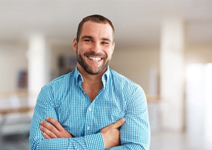Man in button-up shirt smiling with arms folded