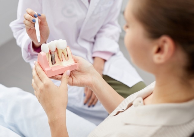 Dentist and patient looking at dental implant model