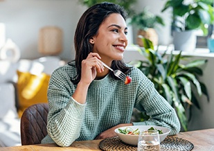 Woman smiling while eating healthy meal at home