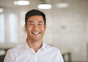 Man in white button up shirt smiling in office