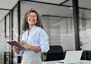 Smiling woman holding tablet in office