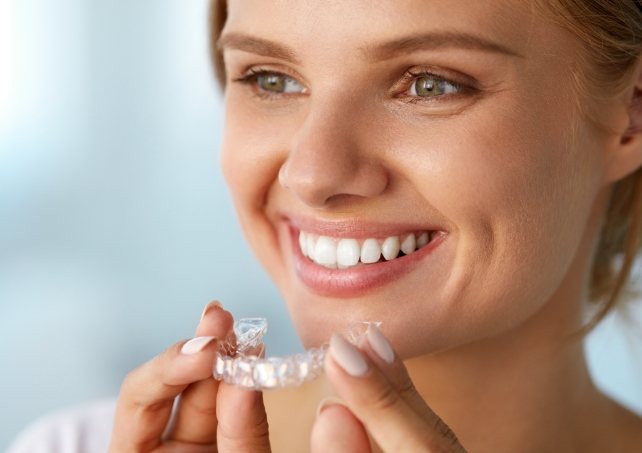 Smiling woman holding an Invisalign tray