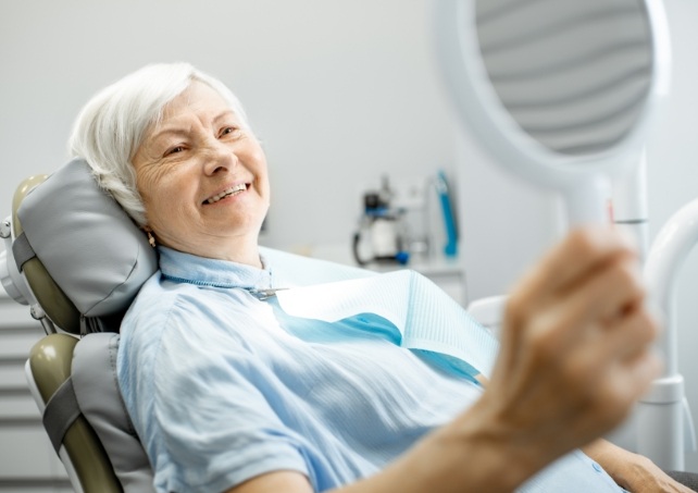 Dental patient with dentures looking at her new smile