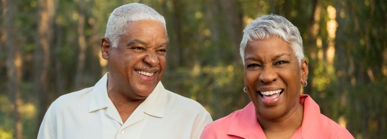 Older man and woman smiling after tooth replacement with dental implants