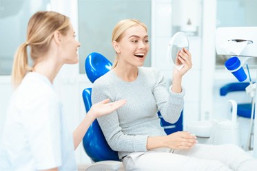 a patient checking her veneers with a mirror