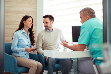 a couple discussing the cost of veneers with their dentist