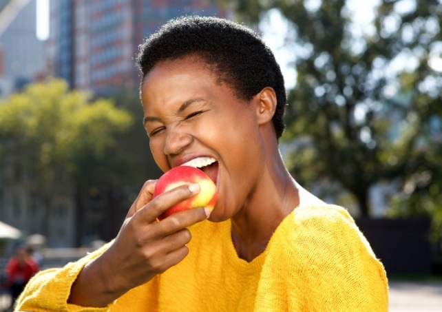 Woman eating an apple and enjoying the benefits of porcelain veneers