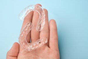 Hand holding 2 clear aligners. 