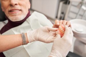Man giving his ill-fitting dentures to his dentist
