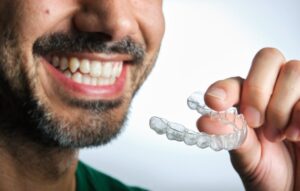 Man smiling and putting on his Invisalign trays