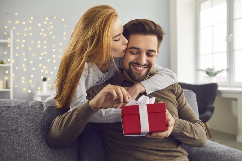 person kissing partner’s head and giving them Valentine’s Day gift