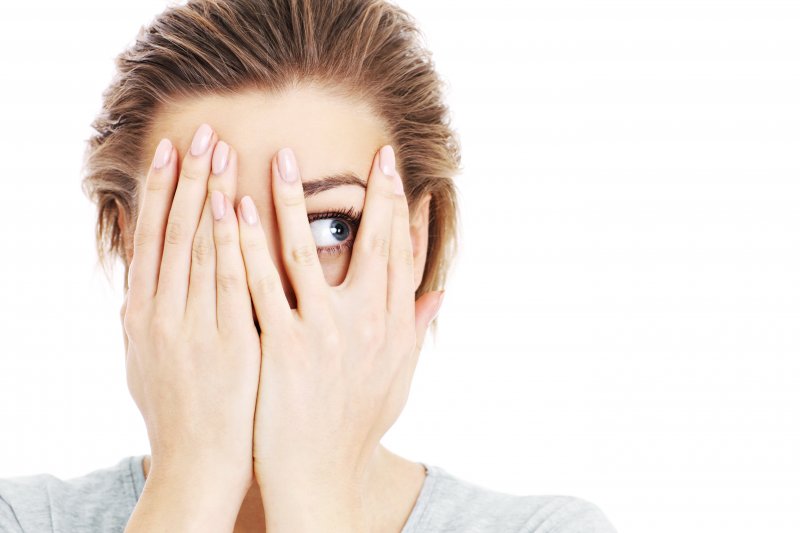 young woman covering her face out of fear