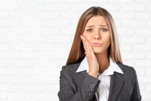 woman holding her jaw in pain